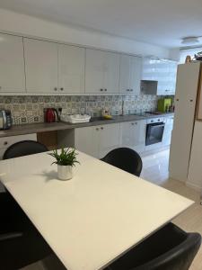 una cocina con armarios blancos y una mesa con una planta. en Private room en Londres
