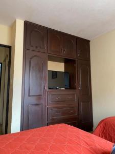 Apartamento #1 Portal de Occidente في كويتزالتنانغو: خزانة خشبية كبيرة في غرفة نوم مع سرير