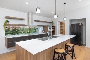 a kitchen with a white counter top and stools at New luxury home, walking distance to CBD in Wagga Wagga
