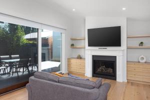 a living room with a couch and a tv and a fireplace at New luxury home, walking distance to CBD in Wagga Wagga