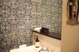 Łazienka z umywalką i niebiesko-białą ścianą wyłożoną kafelkami w obiekcie The Houston Wagga w mieście Wagga Wagga