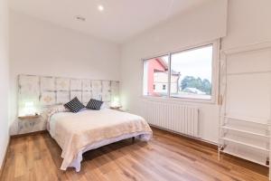 a white bedroom with a bed and a large window at San Pedro in Pontevedra