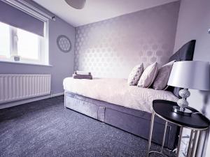een slaapkamer met een bed en een tafel met een lamp bij The Fairfield - Free Parking & Wi-Fi - 5min to Freeman Hospital in Longbenton