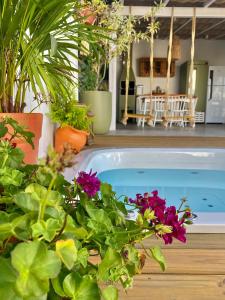 a swimming pool with flowers and plants at Pousada Maria Parafina Praia do Rosa in Imbituba