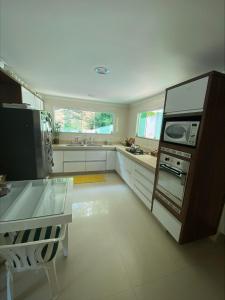 eine große Küche mit weißen Schränken und einer Mikrowelle in der Unterkunft Casa Maravilhosa na Ferradura in Búzios