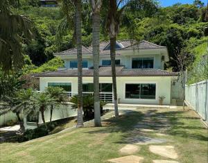 ein weißes Haus mit Palmen davor in der Unterkunft Casa Maravilhosa na Ferradura in Búzios