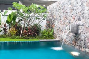 a pool with a water fountain next to a stone wall at Two-bedroom villa with pool in Ban Ang Thong