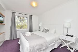 a white bedroom with a large bed and a window at Villa 2br Barbera Villa located within Cypress Lakes Resort in Pokolbin