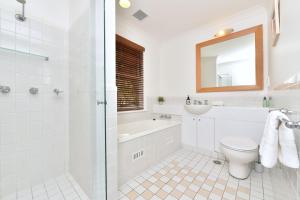 a white bathroom with a tub and a toilet and a sink at Villa 2br Barbera Villa located within Cypress Lakes Resort in Pokolbin