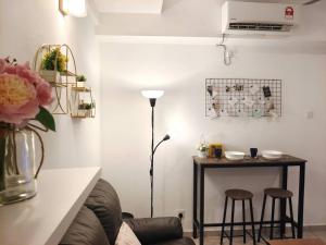 uma sala de estar com uma mesa e dois bancos e um candeeiro em 【NEW】Cozy&Warm Studio@Juru Sentral Icon City em Bukit Mertajam