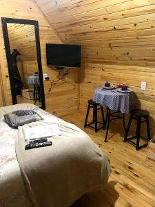 a bedroom with a bed and a table and a tv at Chalé Brisa do Valle in Urubici