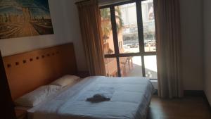 a bed with a robe on it in front of a window at Marina Court Homestay in Kota Kinabalu +7 photos
