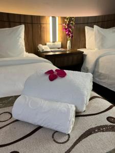a hotel room with two beds with towels and flowers at Nova Hotel Miri in Miri