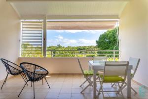 a dining room with a table and chairs on a balcony at Appartement en résidence proche de la plage - Le Mimosa in Sainte-Anne