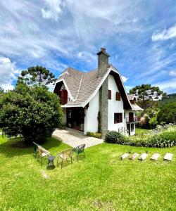 une grande maison blanche avec une cour herbeuse dans l'établissement Casa Três Rios - Campos do Jordão, à Campos do Jordão