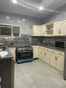 La cuisine est équipée de placards blancs et d'un four avec plaques de cuisson. dans l'établissement Alexander House North Coast, à El Alamein