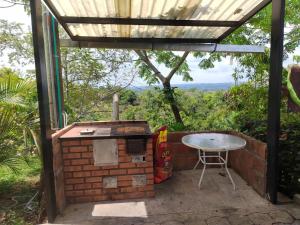 eine Terrasse mit einem Tisch und einem Grill mit Aussicht in der Unterkunft LA POSADA DORADA PARCELAS NAPOLES in Doradal