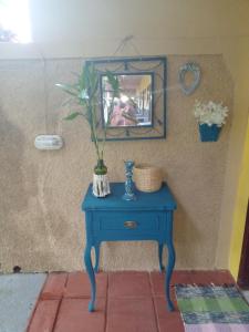 a blue table with a mirror and a vase on it at Pousada Sol das Amendoeiras in Saquarema