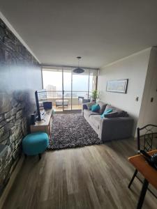 a living room with a couch and a stone wall at Departamento Concón Vista Montemar II in Concón
