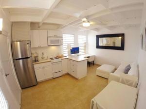 a kitchen with white cabinets and a stainless steel refrigerator at Cozy Beachfront Apartment with Bay views in East End