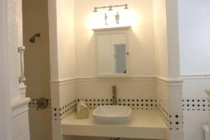 ein weißes Badezimmer mit einem Waschbecken und einem Spiegel in der Unterkunft Cozy Beachfront Apartment with Bay views in East End