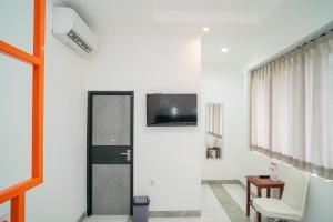 sala de estar con TV en la pared en RedDoorz near Stasiun Senen, en Yakarta