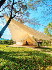 uma grande tenda branca num parque com uma árvore em The Wild Khao Yai em Klang Dong