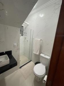 uma casa de banho branca com um WC e um chuveiro em RM hospedagem em Cabo Frio