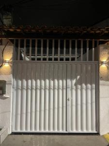 une grande porte métallique avec colonnes blanches sur un bâtiment dans l'établissement RM hospedagem, à Cabo Frio