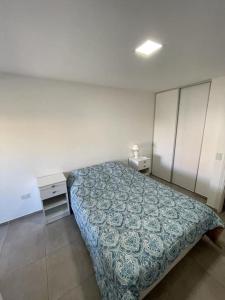 1 dormitorio con 1 cama con colcha azul y mesita de noche en Amplio departamento céntrico balcon terraza asador en Córdoba