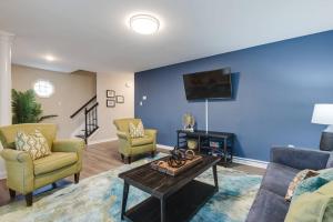 a living room with a couch and chairs and a tv at The Neighborhood House in Richmond in Richmond