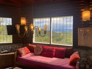 sala de estar con sofá rojo frente a las ventanas en Descanso, aventura y ecoturismo en las sierras in 