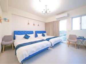 吉安的住宿－藍海筑夢城民宿，一间卧室配有两张床和吊灯。