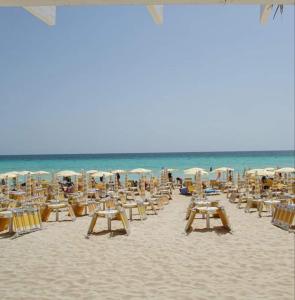 una playa con sillas y sombrillas y el océano en STELLE GEMELLE a 350 mt dalla spiaggia e 50 dal centro, con Wi-fi e completamente accessoriate, en Torre Lapillo