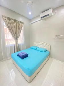 uma cama azul num quarto com uma janela em HZ HOMESTAY PENDANG em Pendang