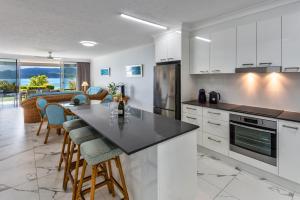 a kitchen with white cabinets and a table with chairs at Frangipani Beachfront Lodge F5 on Hamilton Island by HamoRent in Hamilton Island