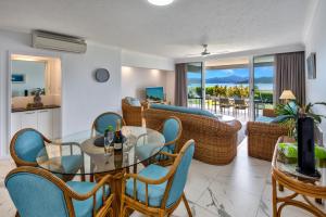 a living room with a glass table and chairs at Frangipani Beachfront Lodge F5 on Hamilton Island by HamoRent in Hamilton Island