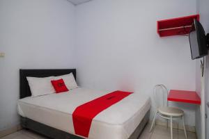 a bedroom with a bed with a red blanket on it at RedDoorz at Lapangan Bandara Sam Ratulangi Manado in Manado
