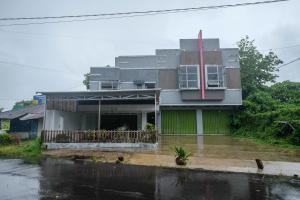 una casa bajo la lluvia con una calle inundada en RedDoorz at Lapangan Bandara Sam Ratulangi Manado, en Manado