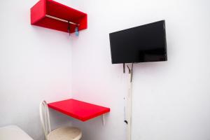 a room with a red table and a tv on a wall at RedDoorz at Lapangan Bandara Sam Ratulangi Manado in Manado