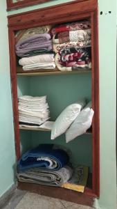 ein Schrank mit vielen Hemden und Kissen in der Unterkunft Maison d’hôtes ATLAS ait alla in Tan-Tan Plage