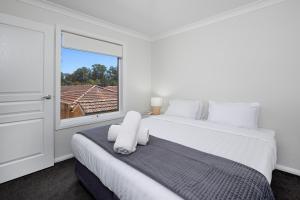 a white bedroom with a large bed and a window at Contemporary Living in the CBD in Wagga Wagga