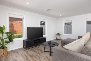 a living room with a couch and a flat screen tv at Contemporary Living in the CBD in Wagga Wagga