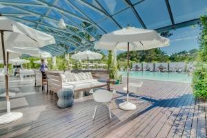 un patio con muebles y sombrillas blancas y una piscina en Apto. en elegante edificio - Punta del Este, en Punta del Este