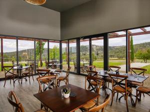 Un restaurante con mesas y sillas y grandes ventanales. en Glenbosch Wine Estate Farm Stays, en Beechworth