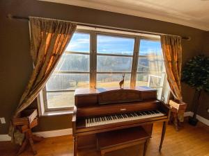 a piano sitting in front of a large window at Mid-Century Vintage Brick Ranch Upstairs Guesthouse in Sevierville
