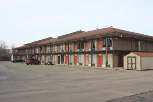 een groot gebouw met rode deuren op een parkeerplaats bij Red Carpet Inn - Louisville in Louisville