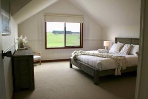 um quarto com uma cama grande e uma janela em Banksia em Port Campbell