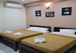 2 Betten nebeneinander in einem Zimmer in der Unterkunft Nilton Bay Residency in Puducherry