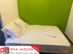 PIA HOME La Pompe في Mamoudzou: سرير في غرفة بجدار أخضر